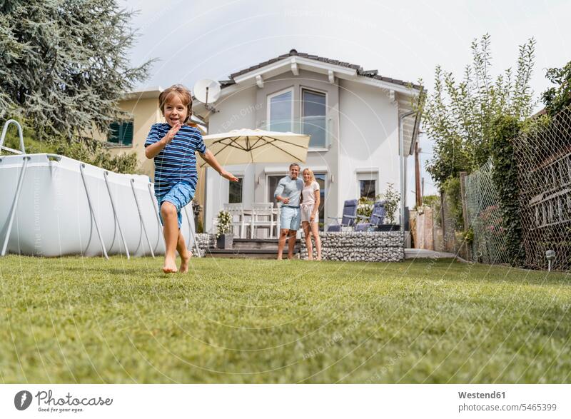 Junge rennt im Garten, während die Eltern zusehen T-Shirts rennen sommerlich Sommerzeit begeistert Enthusiasmus enthusiastisch Überschwang Überschwenglichkeit