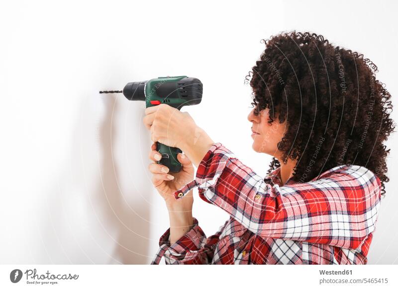 Frau mit tragbarer Bohrmaschine, Markierung mit Bleistift an einer Wand Stifte stehend steht daheim zu Hause DIY Do-it-Yourself Muße Individuell Waende Wände
