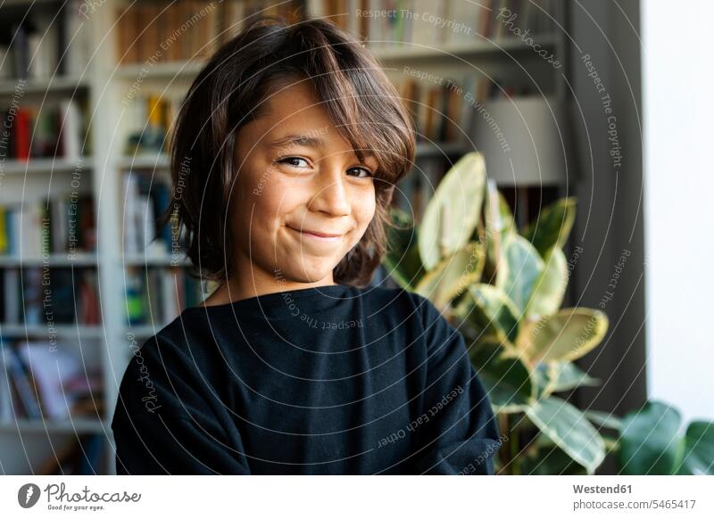 Porträt eines lächelnden Jungen zu Hause Ablage Regale Bücherregale freuen Glück glücklich sein glücklichsein Farben Farbtoene Farbton Farbtöne schwarze