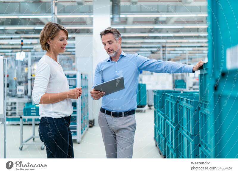 Geschäftsmann und Geschäftsfrau mit Tablettengespräch in einer Fabrikhalle Arbeitskollege Arbeitskollegen Kollege Partner Partnerschaften Job Berufe