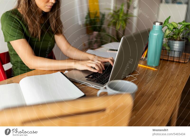 Geschäftsfrau benutzt Laptop am Schreibtisch, während sie im Heimbüro sitzt Farbaufnahme Farbe Farbfoto Farbphoto Spanien Freizeitkleidung Freizeitbekleidung
