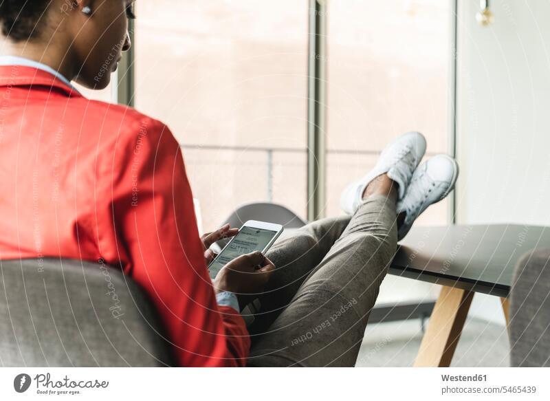 Junge Geschäftsfrau sitzt mit erhobenen Füßen am Schreibtisch und benutzt ein digitales Tablet Arbeitstisch Schreibtische sitzen sitzend entspannt entspanntheit