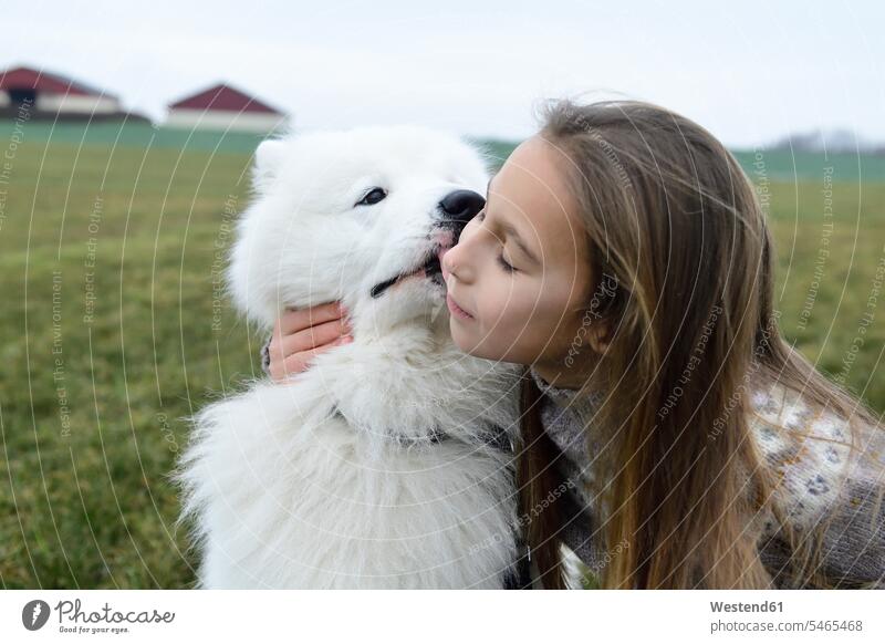 Mädchen und ihr weißer Hund kuscheln auf einer Wiese weiblich Wiesen schmusen knuddeln weißes weiss Kind Kinder Kids Mensch Menschen Leute People Personen Farbe