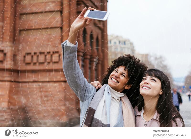 Spanien, Barcelona, zwei glückliche Frauen machen ein Selfie an einem Tor Selfies Freundinnen weiblich Tore Glück glücklich sein glücklichsein Freunde