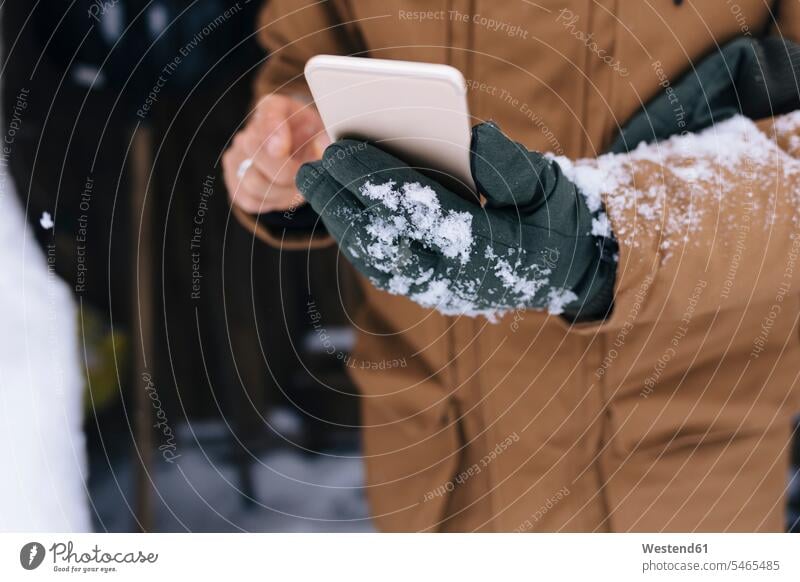 Männerhand hält Smartphone im Winter, Nahaufnahme Handschuhe Telekommunikation Handies Handys Mobiltelefon Mobiltelefone Jahreszeiten winterlich Winterzeit