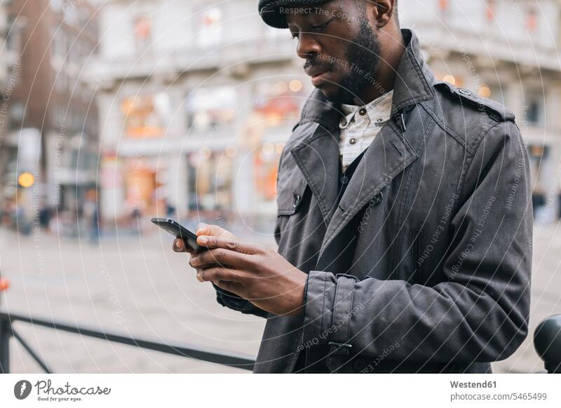 Mann in der Stadt überprüft Mobiltelefon staedtisch städtisch Handy Handies Handys Mobiltelefone checken Männer männlich Außenaufnahme draußen im Freien Telefon