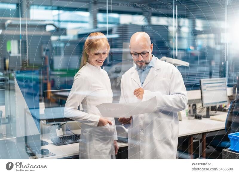 Zwei Techniker in Laborkitteln betrachten einen Plan ansehen Pläne schauen sehend Techniken Technologie Deutschland Kompetenz kompetent Sachverstand