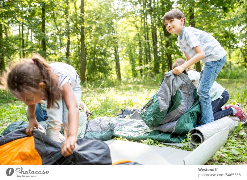 Schulkinder packen ihre Schlafsäcke aus, um im Wald zu zelten Farben Farbtoene Farbton Farbtöne Campen erforschen Erforschung erkunden Erkundung Abenteuer