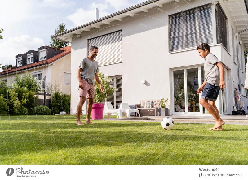 Vater und Sohn spielen Fußball im Garten T-Shirts Bälle Fussball Fußbälle entspannen relaxen sommerlich Sommerzeit freuen Frohsinn Fröhlichkeit Heiterkeit
