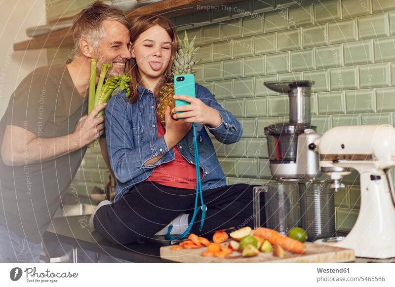 Glücklicher Vater und Tochter in der Küche machen ein Selfie mit Obst und Gemüse freuen Frohsinn Fröhlichkeit Heiterkeit glücklich sein glücklichsein daheim