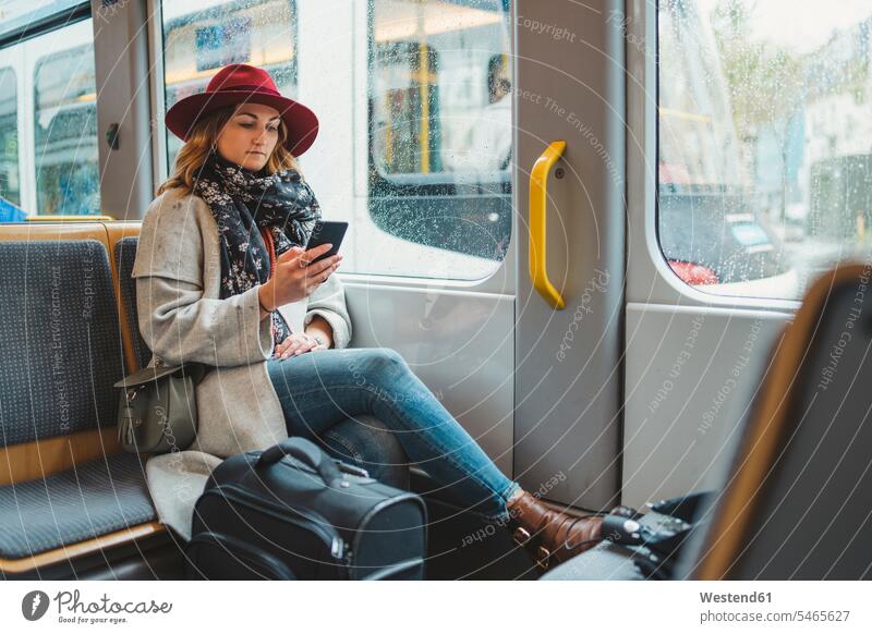 Junge Frau benutzt Handy in einer Straßenbahn Reisegepäck Textnachricht Leute Menschen People Person Personen Europäisch Kaukasier kaukasisch Transport