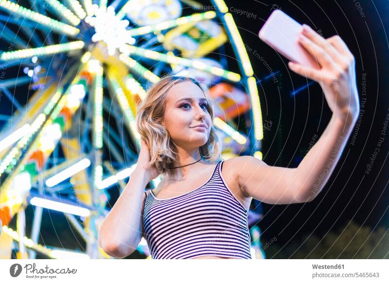 Porträt eines Teenagers, der ein Selfie vor einem Riesenrad auf dem Jahrmarkt macht Smartphone iPhone Smartphones Volksfest Rummelplatz Kirmes Selfies