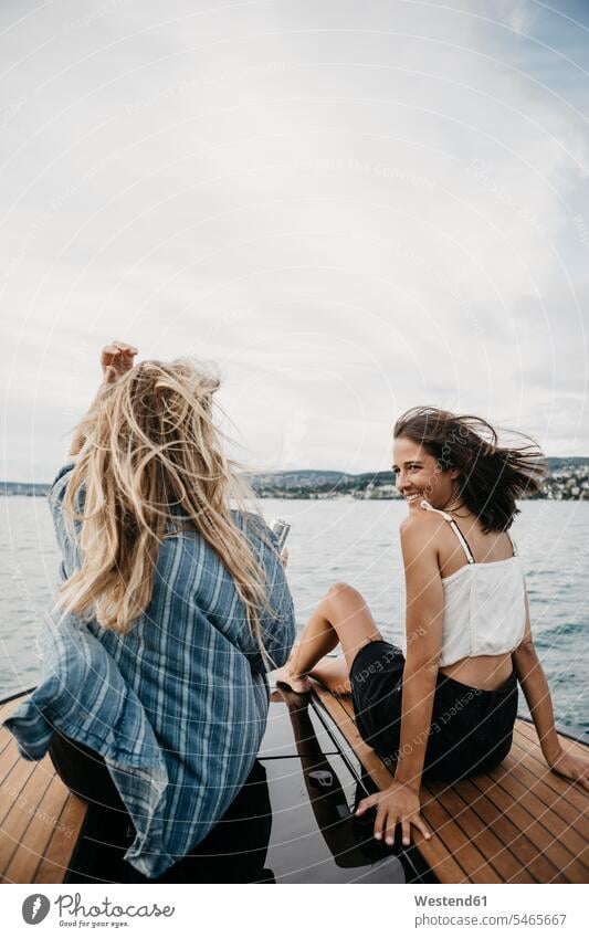 Glückliche Freundinnen bei einer Bootsfahrt auf einem See Freunde Kameradschaft Wasserfahrzeug Boote Motorboote sitzend sitzt reden Jahreszeiten sommerlich