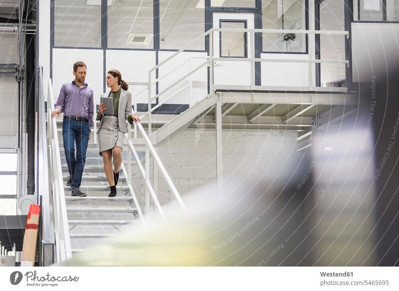 Kollegen in der Firma unterhalten sich auf der Treppe Treppenaufgang Team Werkshalle Werkhalle Businessmann Digitalisierung besprechen diskutieren Besprechung