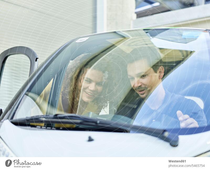 Lächelndes Paar mit elektrischem Seifenblasenauto Auto Wagen PKWs Automobil Autos Pärchen Paare Partnerschaft Kabinenroller Rollermobil lächeln Elektroauto