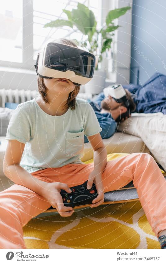 Junge und Vater tragen eine VR-Brille und spielen zu Hause ein Videospiel Sohn Söhne Videospiele Virtuelle Realität Virtuelle Realitaet Papas Väter Vati Vatis