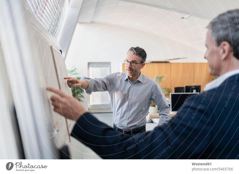 Ein reifer männlicher Unternehmer zeigt während eines Treffens auf einen Geschäftsmann im Büro, während er ihm die Strategie erklärt Farbaufnahme Farbe Farbfoto