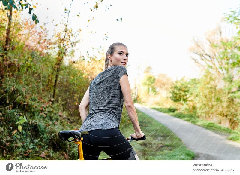 Rückansicht einer sportlichen jungen Frau mit Fahrrad in einem Park weiblich Frauen Bikes Fahrräder Räder Rad Parkanlagen Parks Erwachsener erwachsen Mensch
