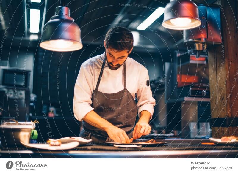 Chefkoch, der in der Küche eines Restaurants Speisen auf Tellern serviert Leute Menschen People Person Personen Europäisch Kaukasier kaukasisch 1 Ein ein Mensch