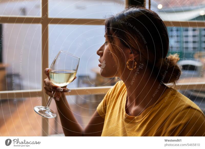 Schöne Lateinamerikanerin trinkt Weißwein an der Bar Farbaufnahme Farbe Farbfoto Farbphoto Freizeitkleidung Freizeitbekleidung casual Freizeitbeschäftigung Muße