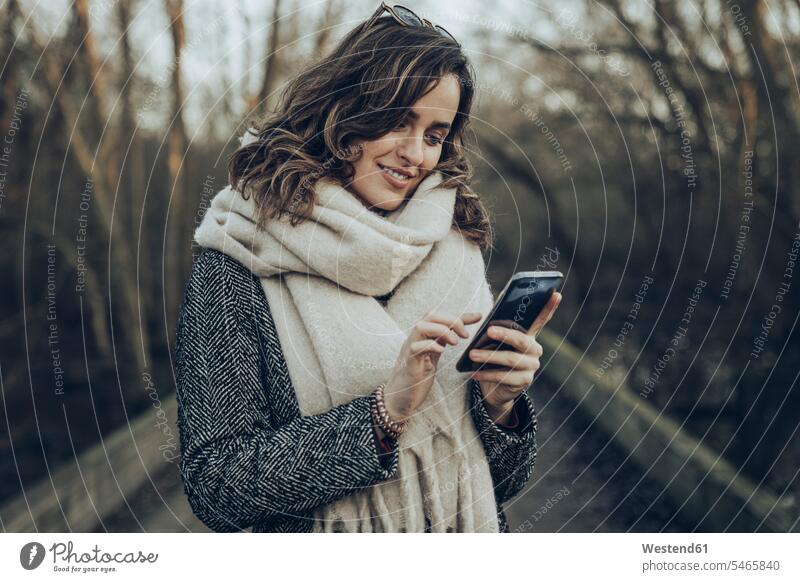 Porträt einer jungen brünetten Frau mit Smartphone Jacke Mäntel Travel Leute Menschen People Person Personen Europäisch Kaukasier kaukasisch benützen nutzen