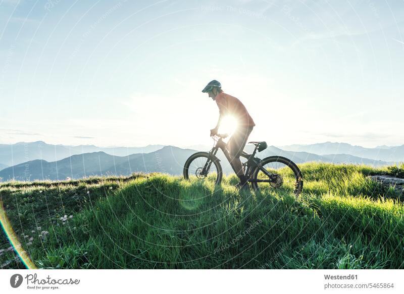 Mountainbiker gegen die Sonne auf einem Weg in Graubünden, Schweiz Raeder Räder Bike Bikes Fahrräder Rad fahrend fahrende fahrender fahrendes Muße mountainbiken