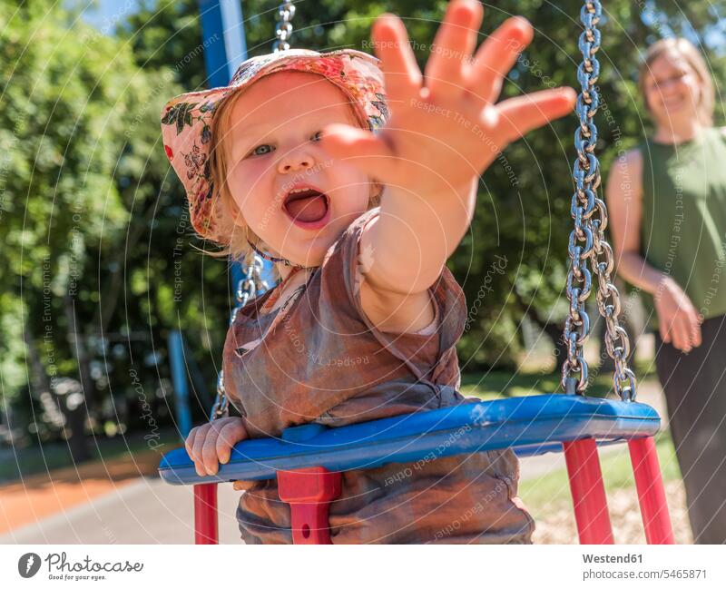 Porträt eines glücklichen kleinen Mädchens mit ihrer Mutter auf dem Spielplatz Schaukeln Griff rufen rufend Schrei schreiend sommerlich Sommerzeit freuen