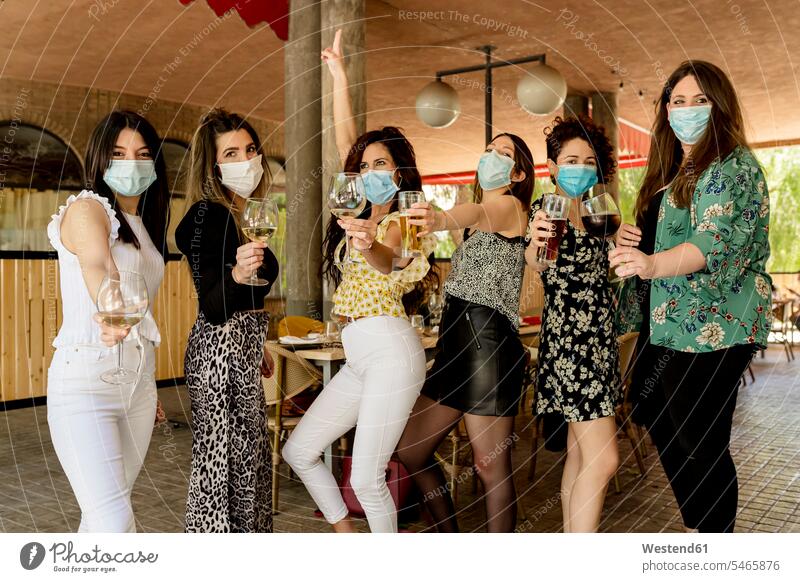 Junge weibliche Kunden, die während einer Pandemie Getränke halten, während sie im Restaurant stehen Farbaufnahme Farbe Farbfoto Farbphoto Spanien Innenaufnahme