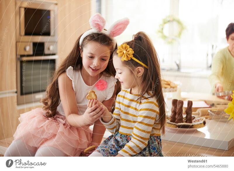 Zwei Mädchen schauen Keks in der Küche an Kekse Plaetzchen Plätzchen Schwester Schwestern ansehen weiblich Gebäck Backware Gebaeck Backwaren Süßspeise Süsses
