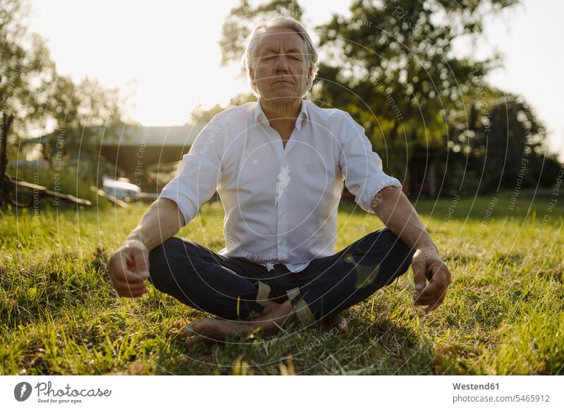 Mann praktiziert Yoga, während er im Hof in Lotus-Position sitzt Farbaufnahme Farbe Farbfoto Farbphoto Ganzkörperansicht Ganzansicht Ganzkörperaufnahme
