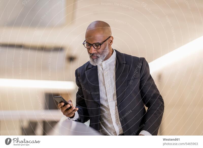 Porträt eines glatzköpfigen reifen Geschäftsmannes, der auf sein Handy schaut Businessmann Businessmänner Geschäftsmänner Smartphone iPhone Smartphones Portrait