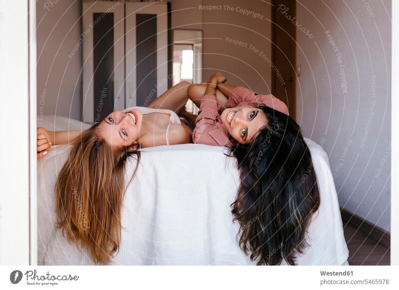 Junge Freunde mit langen Haaren liegen zu Hause auf dem Bett Farbaufnahme Farbe Farbfoto Farbphoto Innenaufnahme Innenaufnahmen innen drinnen Tag