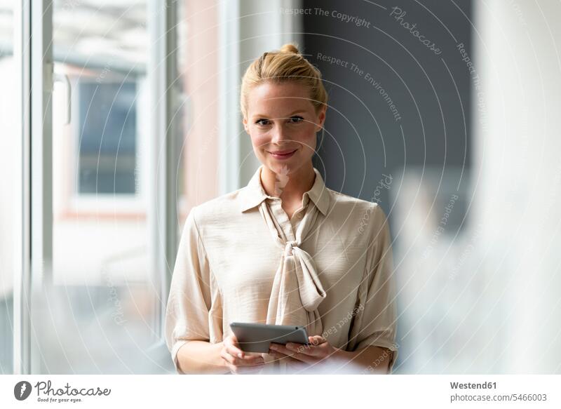 Porträt einer lächelnden jungen Geschäftsfrau mit Tablette am Fenster Job Berufe Berufstätigkeit Beschäftigung Jobs geschäftlich Geschäftsleben Geschäftswelt