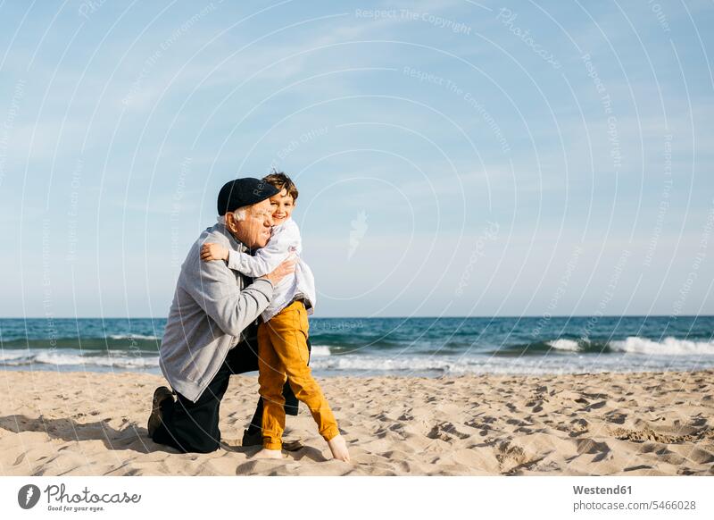 Großvater und Enkel umarmen sich am Strand Urgroßvater Uropa Uropas Urgroßväter Küste Kueste Kuesten Küsten Frühling Frühjahr Lenz Horizont Horizonte