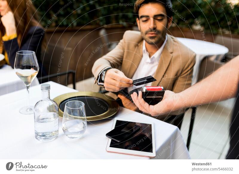 Mann zahlt mit Kreditkarte in einem Restaurant Lokal Speiserestaurant Lokale Speiselokale Restaurants Speiserestaurants Männer männlich bezahlen EC-Karte
