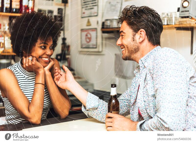 Mann hält Bierflasche in der Hand und berührt Barkeeperin, während er am Tresen mit ihr flirtet Farbaufnahme Farbe Farbfoto Farbphoto Innenaufnahme