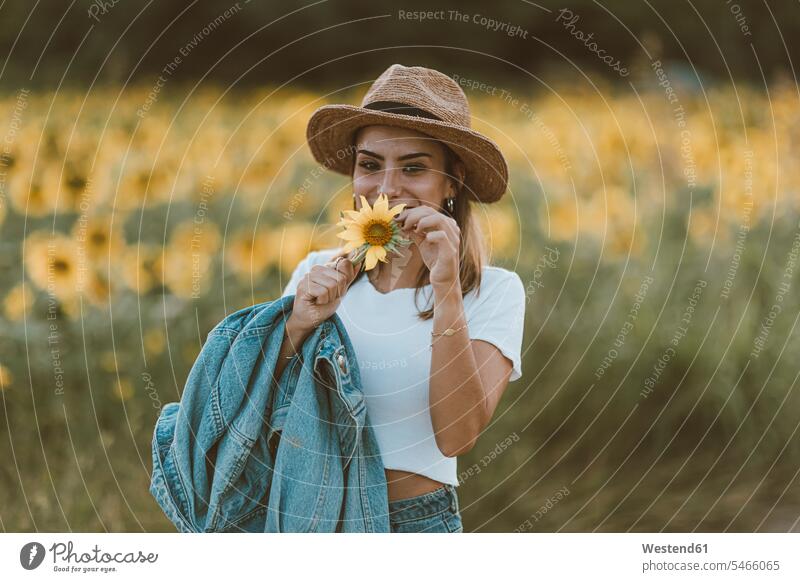 Bildnis einer jungen Frau mit blauer Jeansjacke und Hut in einem Sonnenblumenfeld Hüte abends freuen geniessen Genuss Glück glücklich sein glücklichsein