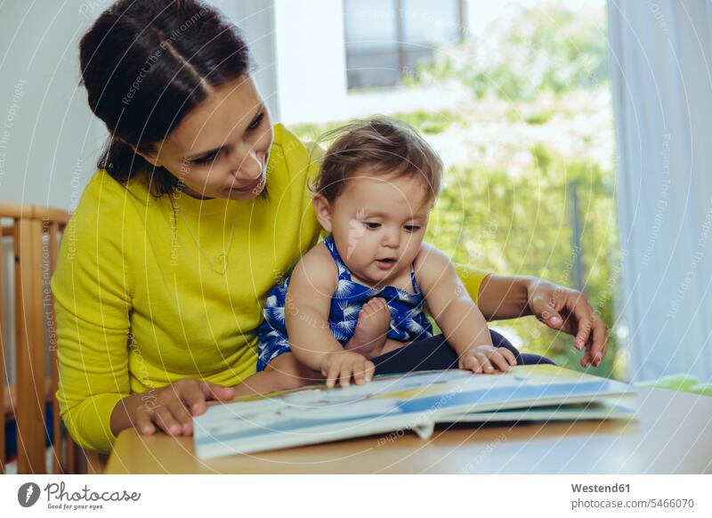 Mutter und kleine Tochter schauen sich ein Kinderbuch an Töchter ansehen Baby Babies Babys Säuglinge Mami Mutti Mütter Mama Kinderbuecher Kinderbücher Familie