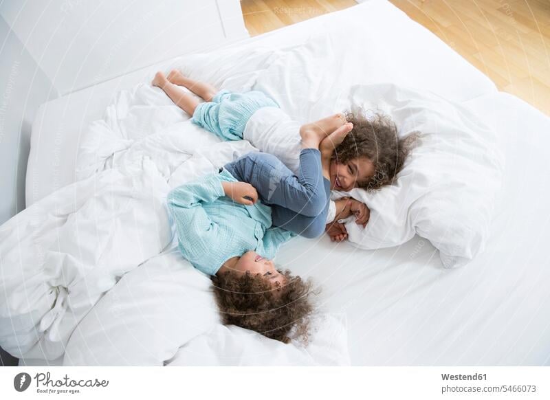 Zwei glückliche Zwillingsbrüder tummeln sich im Bett Leute Menschen People Person Personen gelockt gelockte Haare gelocktes Haar lockig lockiges Haar Betten