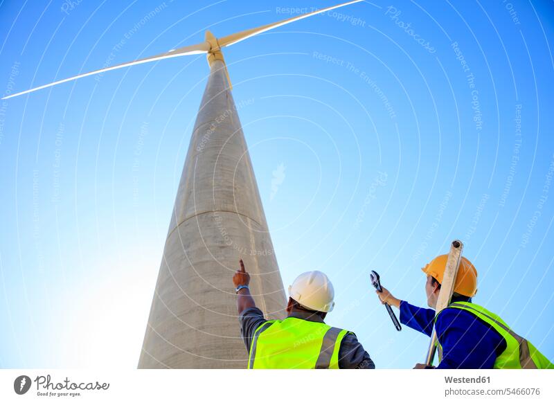 Niedriger Blickwinkel der Techniker vor der Windkraftanlage Windturbine Windrad Windräder Techniken Technologie Windenergie Stromerzeugung Erneuerbare Energie