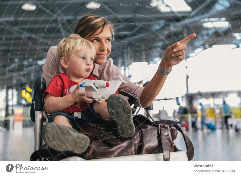 Deutschland, Köln, Porträt von Mutter und kleinem Sohn mit Gepäckwagen am Flughafenterminal Flughaefen Flugplätze Airport Flugplaetze Airports Terminals