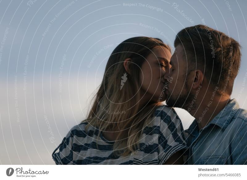 Junges Paar küsst sich im Freien küssen Küsse Kuss Pärchen Paare Partnerschaft Mensch Menschen Leute People Personen Passion Leidenschaft Natur Gemeinsamkeit