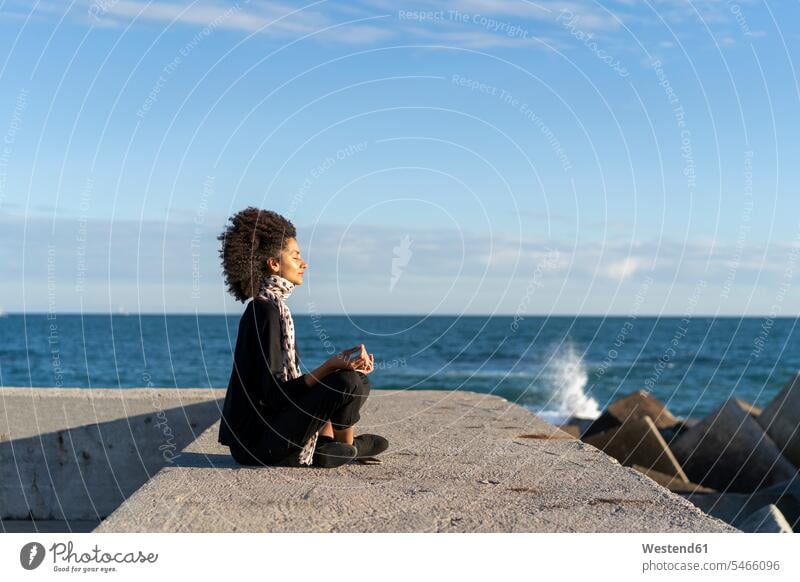 Frau sitzt auf Wand vor dem Meer meditieren Meere weiblich Frauen Mauer Mauern sitzen sitzend Gewässer Wasser Erwachsener erwachsen Mensch Menschen Leute People