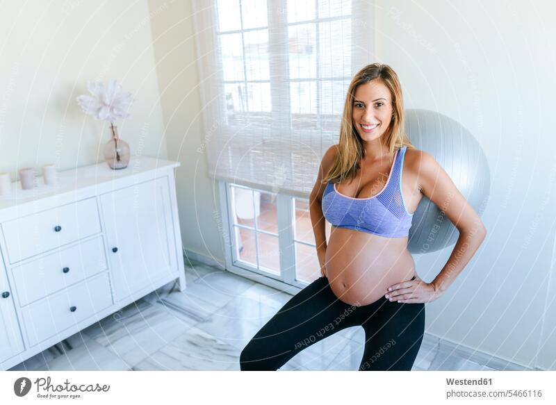 Porträt einer lächelnden schwangeren Frau, die mit einem Fitnessball übt Schwangere schwangere Frau weiblich Frauen Portrait Porträts Portraits Gymnastikball