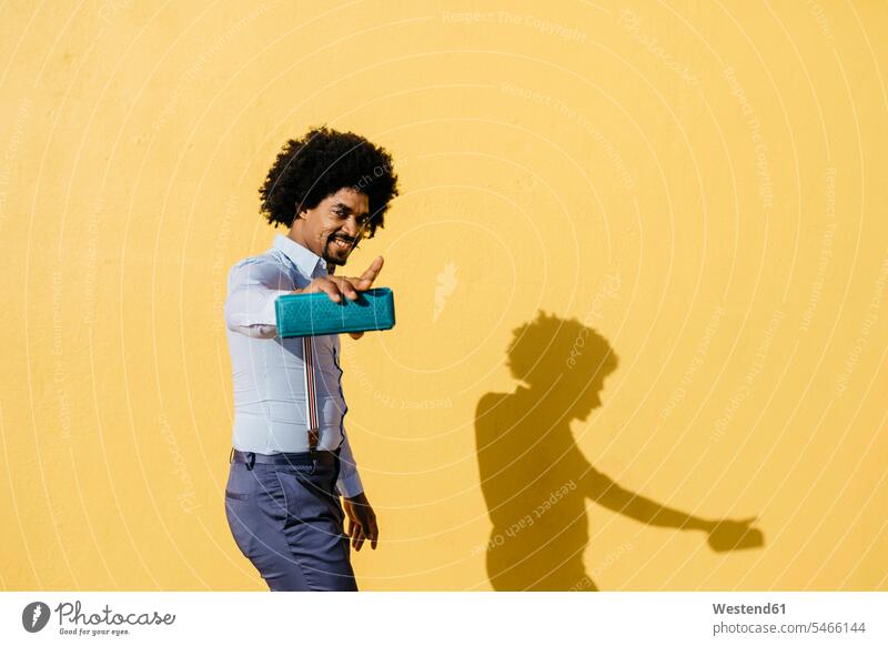 Lächelnder Mann mit Lautsprecher hört Musik und tanzt vor einer gelben Wand Männer männlich gelber gelbes lächeln Mauer Mauern hören hoeren Erwachsener