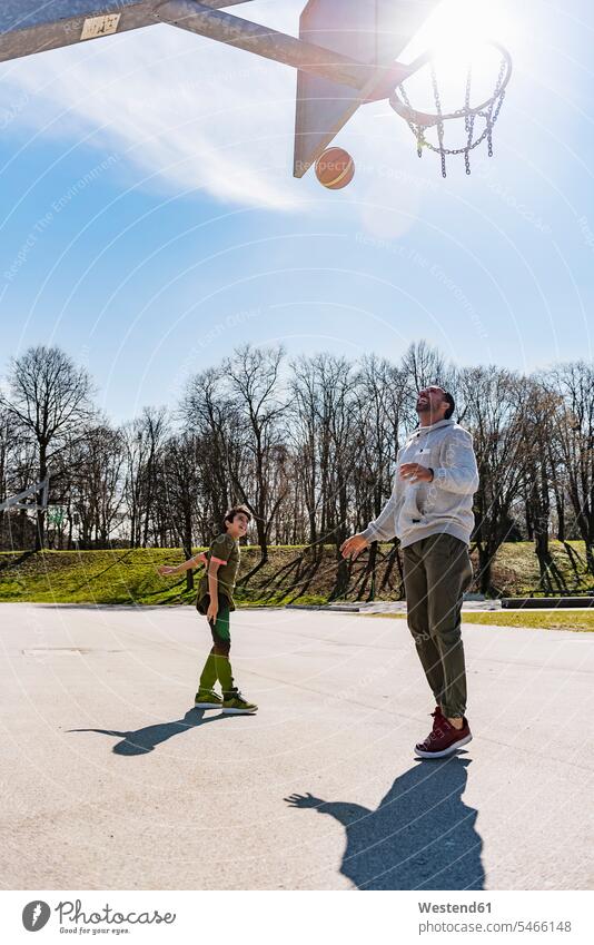 Vater und Sohn spielen Basketball auf dem Platz im Freien Söhne Papas Väter Vati Vatis Papis Basketbaelle Basketbälle Basketballfeld Basketballplatz