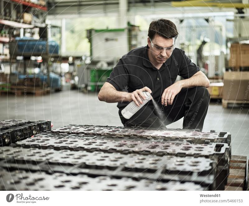 Arbeiter in einer metallverarbeitenden Fabrik beim Sprühen eines Zylinderkopfes sprühen spruehen Fabriken Werkstatt Werkstätte Werkstaette Werkstaetten