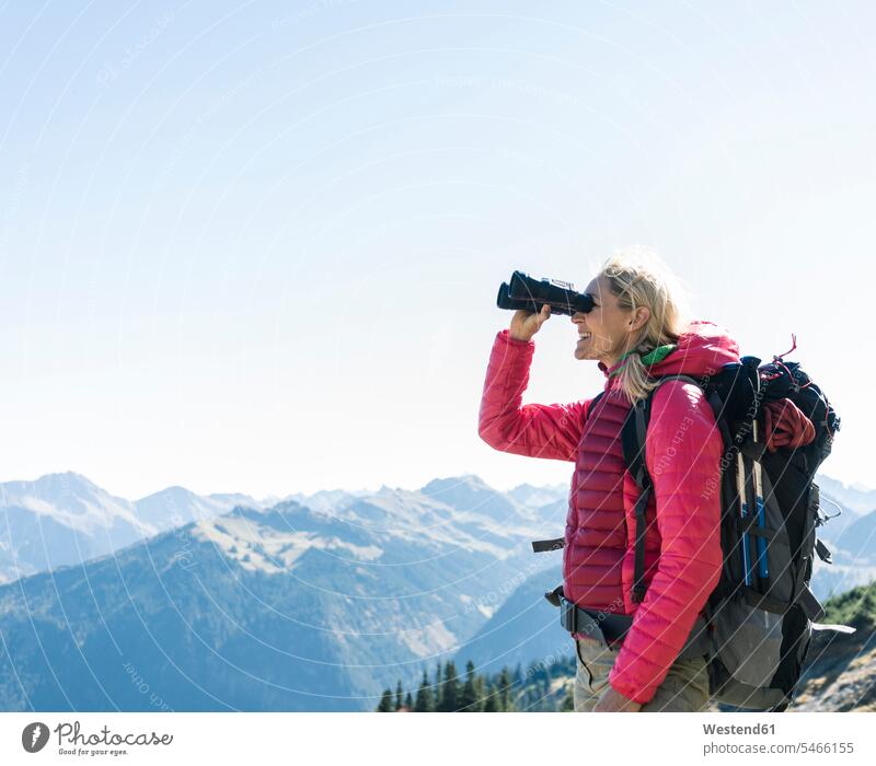 Österreich, Tirol, glückliche Frau schaut beim Wandern durch ein Fernglas Glück glücklich sein glücklichsein Wandertour weiblich Frauen wandern Wanderung