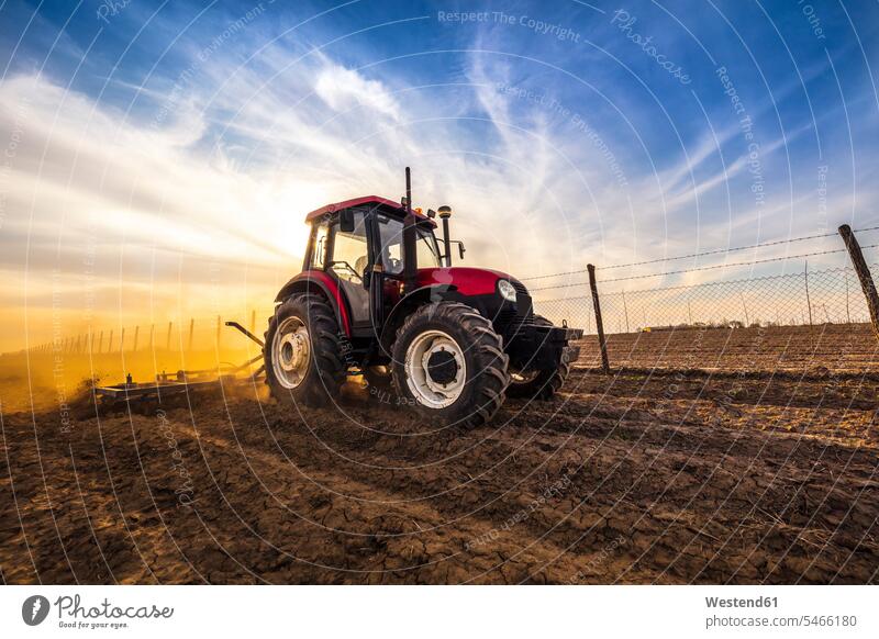 Mann mit Traktor pflügt landwirtschaftliches Land gegen bewölkten Himmel Farbaufnahme Farbe Farbfoto Farbphoto Tag Tageslichtaufnahme Tageslichtaufnahmen