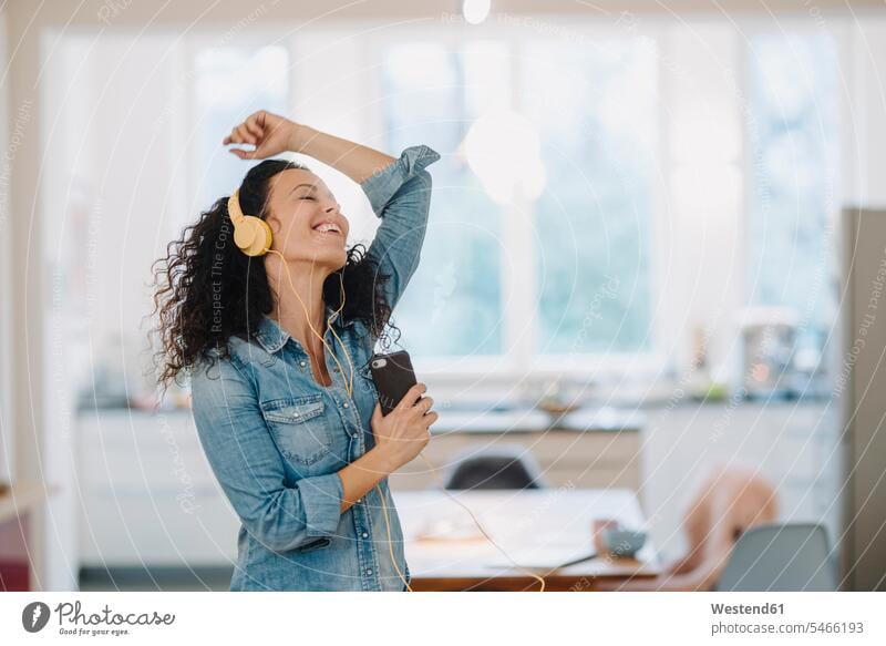 Glückliche Frau, die Musik hört, singt und tanzt, mit Smartphone und Kopfhörern Leute Menschen People Person Personen Europäisch Kaukasier kaukasisch 1 Ein